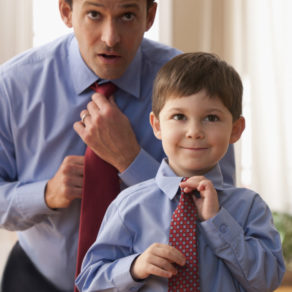 Father and son fixing ties together